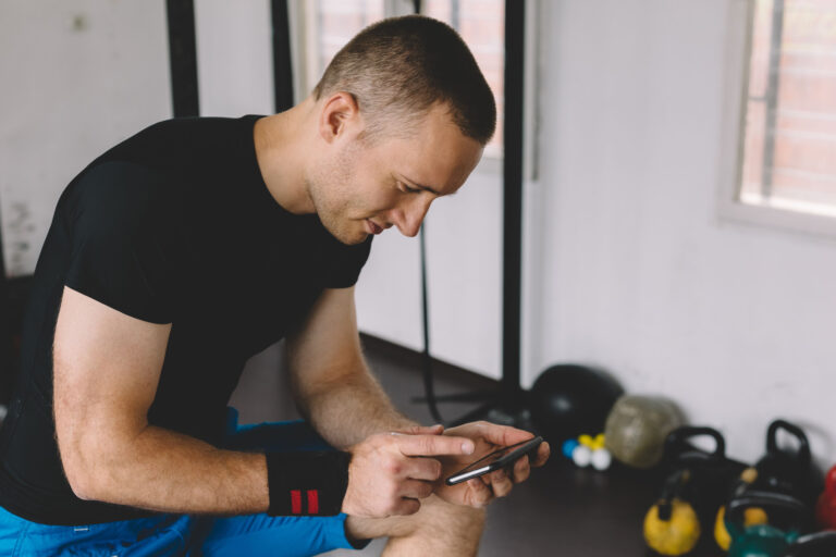 Man in a gym while on his phone looking focused